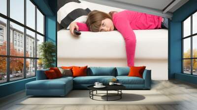 bored little girl lying on the sofa watches TV during the Coronavirus quarantine Wall mural