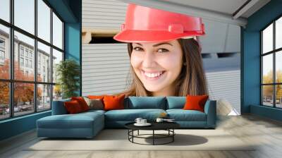 Beautiful girl wearing a red safety helmet on construction site Wall mural