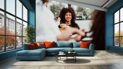 Beautiful latin woman with short curly brown hair getting a treat at the hairdresser. Latin hairdresser working her afro hair. Lifestyle Wall mural