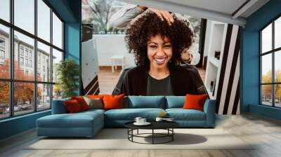 Beautiful latin woman with short curly brown hair getting a treat at the hairdresser. Latin hairdresser working her afro hair. Lifestyle Wall mural