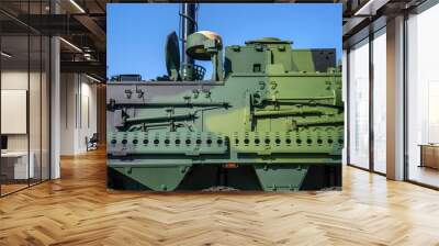 Armoured vehicle side green steel plating, close-up detail to pole, shovel and other tools mounted on wall Wall mural