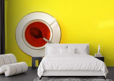 Flat lay photo, white porcelain cup of hot tea with silver spoon, on yellow board, space for text right Wall mural