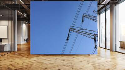 Looking up steel power pylon construction with high voltage cables against blue sky. Wide banner for electric energy industry with space for text on left side Wall mural