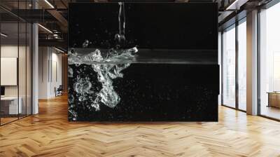 Water splashing as it's poured into aquarium tank, black background Wall mural