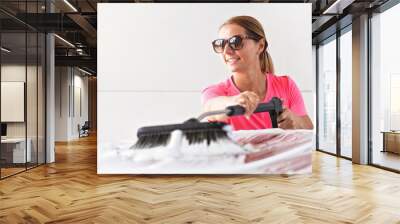 Young woman wearing pink t shirt and sunglasses cleaning her car in self service carwash Wall mural