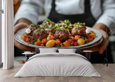 Chef holding plate of gourmet meatballs and roasted vegetables Wall mural