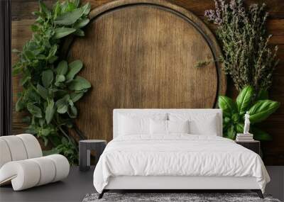 Fresh herbs lying on empty round wooden cutting board Wall mural