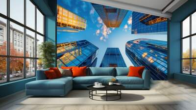 Looking up at the towering modern glass skyscrapers against a backdrop of a clear, blue sky, representing modernity and architectural brilliance. Wall mural