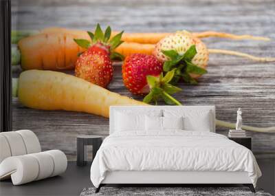 Carrots and three ripe strawberries lie on wooden Board. Wall mural