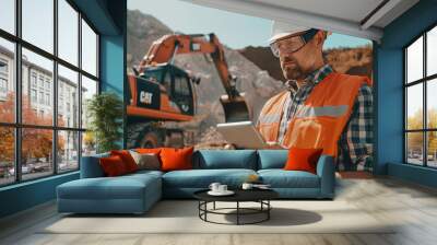 Caucasian Male Civil Engineer Wearing Protective Goggles And Using Tablet On Construction Site On Sunny Day. Man Inspecting Building Progress. Excavator Loading Materials Into Big Industrial Truck. Wall mural