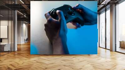 close up of a person playing and holding a joystick with blue light, gaming concept Wall mural