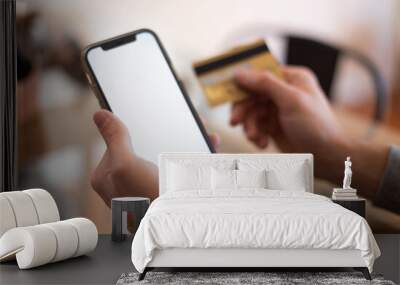 close up young man holding bank credit card and modern tech device with mock up white screen in hand Wall mural