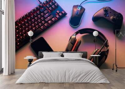 Gamer work space concept. gaming set up. top view of a gaming gear, keyboard, mouse, gamepad, joystick, headset and a smartphone on a colorful desk Wall mural