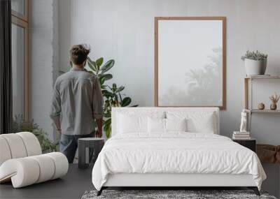 man looking at empty mockup frame, back view Wall mural