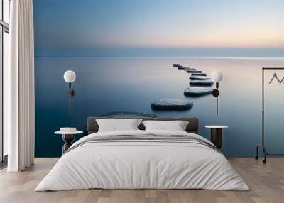 A serene image of large stepping stones leading across a calm sea during sunrise. Wall mural