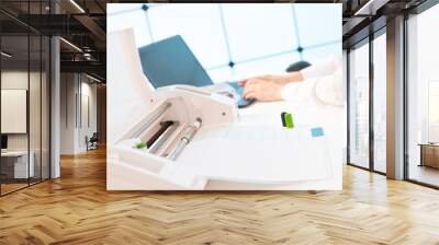 Young woman in the office of the printing company sets up a plotter for printing advertising brochures Wall mural