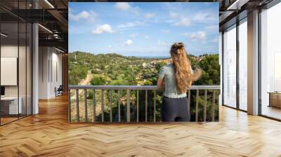 Young woman looking at the scenery from a balcony on asunny day Wall mural