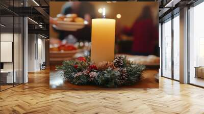 A close-up of a candle centerpiece on a Christmas table, with blurred people passing food around in the background Wall mural