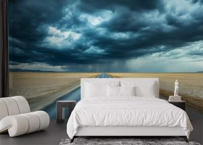 A straight road cutting through a flat, barren landscape under dramatic stormy skies Wall mural