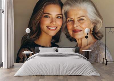 A younger woman and an older woman, both beautifully dressed, standing together with subtle smiles, highlighting their different ages but shared grace Wall mural