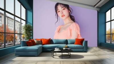 Young Asian woman wearing a pale coral dress, softly posing against a pastel purple background, leaving space for copy Wall mural