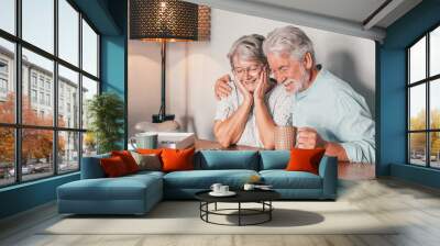 Carefree senior couple at home spend time together doing a puzzle on the wooden table. Elderly man and woman enjoying free time in retirement Wall mural