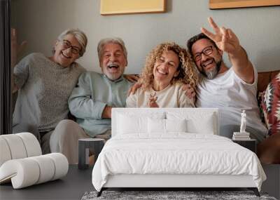 Group of family relaxing on sofa at home having fun and laughing. Handsome  people, parents and adult sons, two generations looking at camera Wall mural