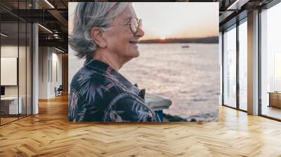 Handsome senior woman at the sea port enjoying free time and relax at sunset light. Elderly caucasian lady on travel or retirement Wall mural