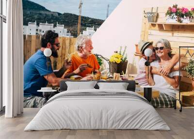 Happy adult people and one teenager smiling and eating. Multi generation family enjoy breakfast together. Senior couple with son and nephew. Wooden table and background Wall mural