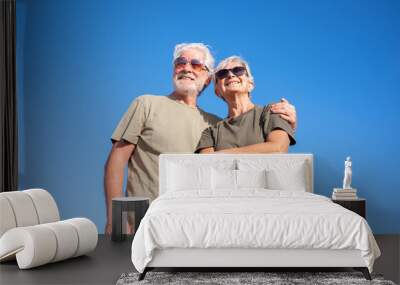 Happy caucasian senior couple  hug in outdoors excursion. Beautiful smiling white-haired elderly couple enjoying retirement and freedom, blue sky on background Wall mural