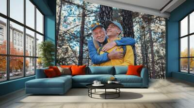 Happy family couple of grandfather and young grandson hugging while hiking in the mountains expressing joy and freedom, healthy lifestyle together in the woods. Adventure is ageless Wall mural