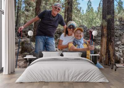 Happy group of senior friends enjoying vacation and adventure trekking in the forest, two elderly women and one man looking at camera smiling. Sport, freedom, healthy lifestyle concept Wall mural