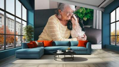 Senior woman exchange cuddles with her cavalier king Charles dog sitting together on home sofa. Pet therapy and best friend concept Wall mural