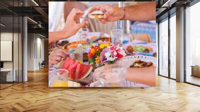 Sharing food with the family. Caucasian peoples enjoying brunch or meal together. Fruits and vegetables on the wooden table. Sunlight outdoor on the terrace Wall mural