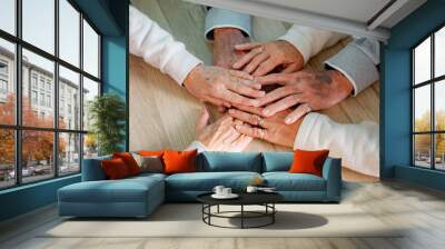 Top view of hands of three old people put in circle show unity and support, together on wooden surface demonstrate eternal friendship love and care. Family value concept Wall mural