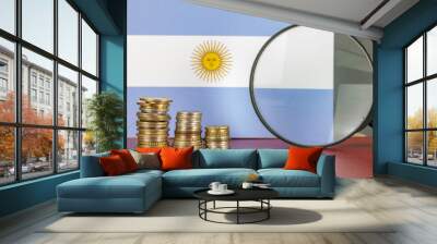 Magnifying glass and coins in front of Argentina flag, country economy concept Wall mural