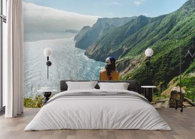 Girl overlooking Madeira volcano cliffs and hilly cliff shore Wall mural