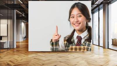 pretty asian woman in university student uniform isolated white background pointing finger to the side Wall mural