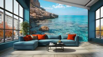 Picturesque view of rough rocky cliff located near rippling water under blue cloudless sky on parrot beach Wall mural