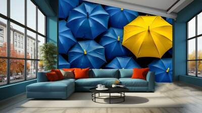 Yellow umbrella standing out among blue umbrellas Wall mural