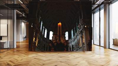 one lit candle inside a dark church Wall mural