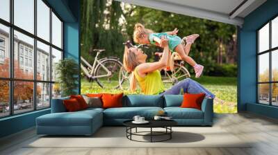 family, happiness, childhood and people concept - Young mother raising her girl child up. Wall mural