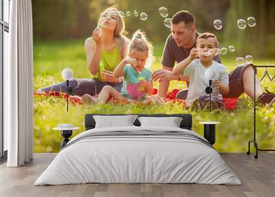 Happy family with children blow soap bubbles outdoor. Wall mural