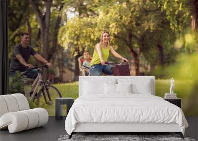 Smiling father and mother with kid on bicycles having fun in park.. Wall mural