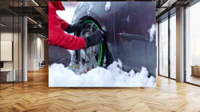 Snow chains on the wheels of car. man tries to put snow chains on tires Clutching the snow chains.. Wall mural