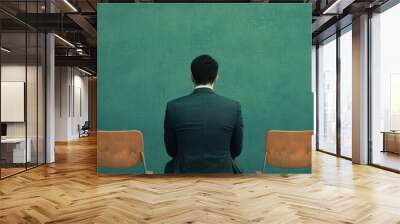 Person in a suit sitting alone on a row of empty chairs against a green wall, symbolizing unemployment, retraining, and support concept Wall mural