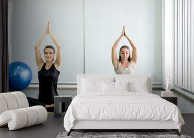 Two Caucasian women exercise doing the yoga pose stretching at home, healthy lifestyle concept Wall mural