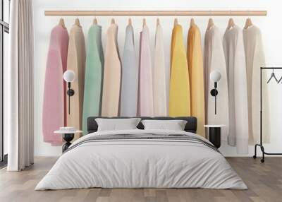 A colorful collection of hanging sweaters on a wooden rack, showcasing soft fabrics and pastel shades for a cozy style. Wall mural