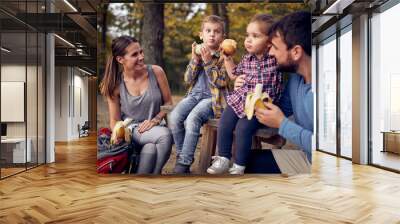 A couple and their children enjoying eating fruits in the forest Wall mural