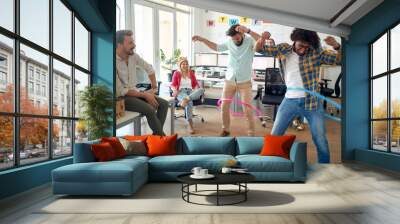 A group of employees is having fun while playing with hula-hoop in the office. Employees, job, office Wall mural